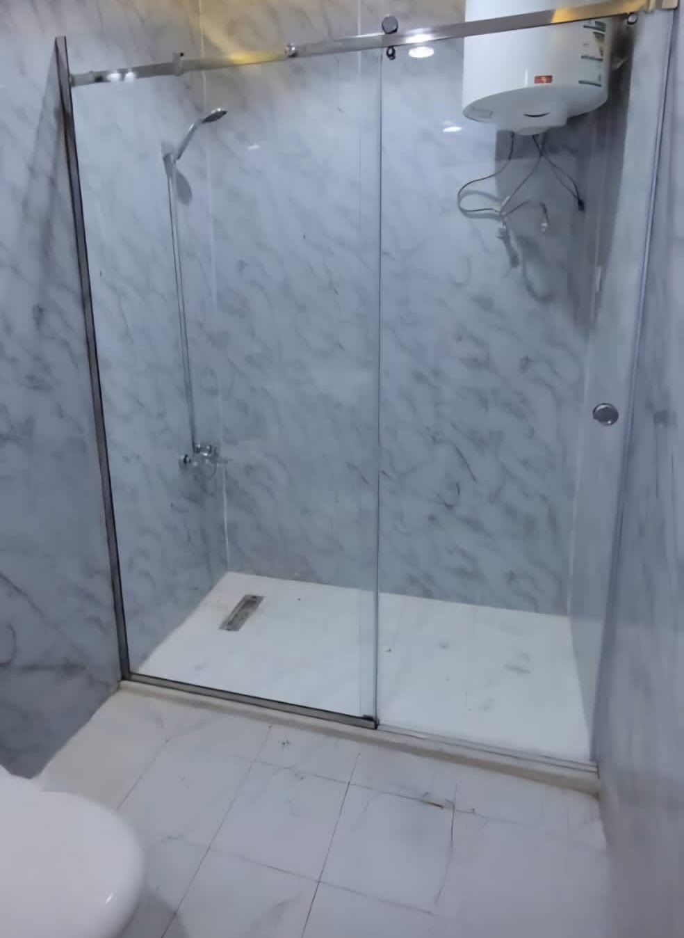 تركيب مراوش وشور زجاج — باب شور زجاجي منزلق بمسار ستيل في حمام رخامي — السعودية — السعيد للزجاج